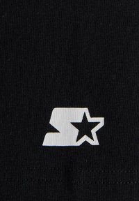 Juodas medvilnės audinys su baltu logotipu, vaizduojančiu stilizuotą raidę "S" ir žvaigždę, esantį prieš tekstūruotą fono.