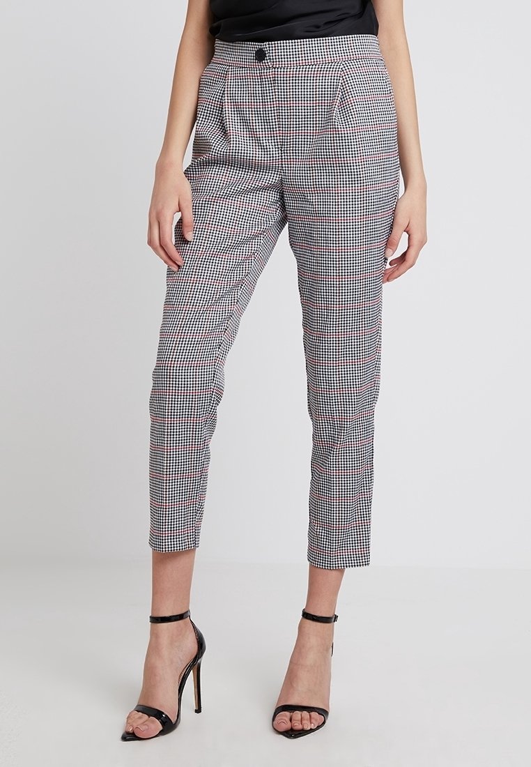 Kostkované kalhoty s vysokým pasem v černé, bílé a červené barvě s předními sklady a zúženými nohavicemi. Kombinované s černými sandály na podpatku.