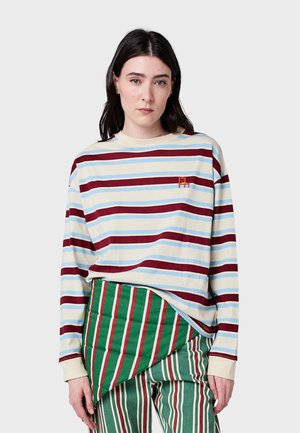 Langärmliges gestreiftes Oberteil in Creme, Blau und Burgunderrot. Mit rundem Ausschnitt und gesticktem Logo. Kombiniert mit grün und rot gestreiften Hosen.