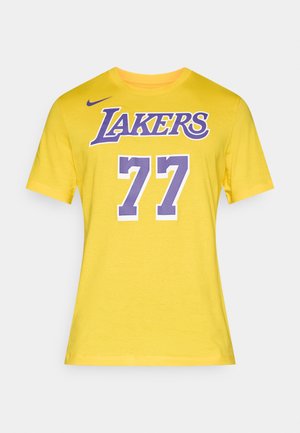Żółta koszulka z krótkim rękawem z napisem "LAKERS" w fioletowym kolorze nad numerem "77" w białym kolorze z fioletowymi akcentami. Wykonana z miękkiego materiału.