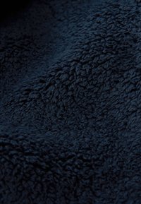 Dunkel marineblauer Fleece-Stoff mit einer weichen, strukturierten und leicht zerknitterten Oberfläche.