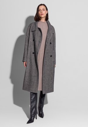 Szary płaszcz z mieszanki wełny o dwurzędowym kroju, dużymi klapami i czarnymi guzikami, noszony na jasnobeżowej sukience i wysokich czarnych botkach.