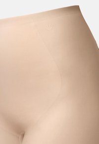 Beiget korkeavyötäröiset muotoilevat shortsit, jotka on valmistettu sileästä kankaasta ja joissa on hienovarainen logopainatus sekä saumaton muotoilu virtaviivaisen istuvuuden takaamiseksi.