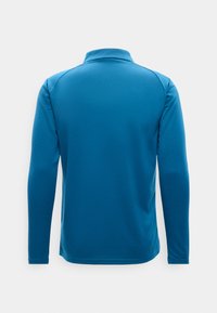 Μπλε αθλητικό πουκάμισο μακρυμάνικο με ψηλό γιακά, εμφανιζόμενο από πίσω σε απλό φωτεινό φόντο.