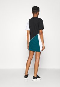 Robe à panneaux colorés comprenant des sections noires, blanches et bleu sarcelle. Manches courtes et col rond. Confectionnée dans un tissu doux et léger.