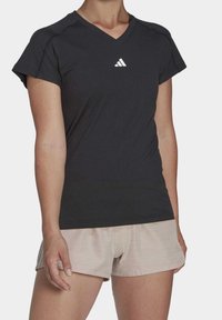 Maglietta atletica nera con maniche corte e scollo a V. Presenta un piccolo logo bianco a tre strisce sul petto. Tessuto morbido e liscio.