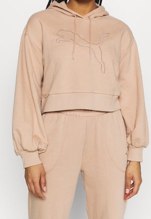 Avskuren beige hoodie med en känguruficka, elastiska ärmslut och en broderad logotyp. Tillverkad av mjukt tyg med en avslappnad passform.