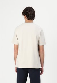 Beige bomull t-skjorte med korte ermer, rund hals og en avslappet passform. Glatt tekstur med minimale sømdetaljer, uten synlige logoer.
