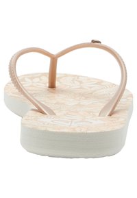 Ruusukultainen, thong-tyylinen flip-flop, jossa on kukkakuosi vaalean persikanvärisellä pohjalla ja valkoisella ulkopohjalla. Tekstuuriset hihnat pitävyyttä varten.