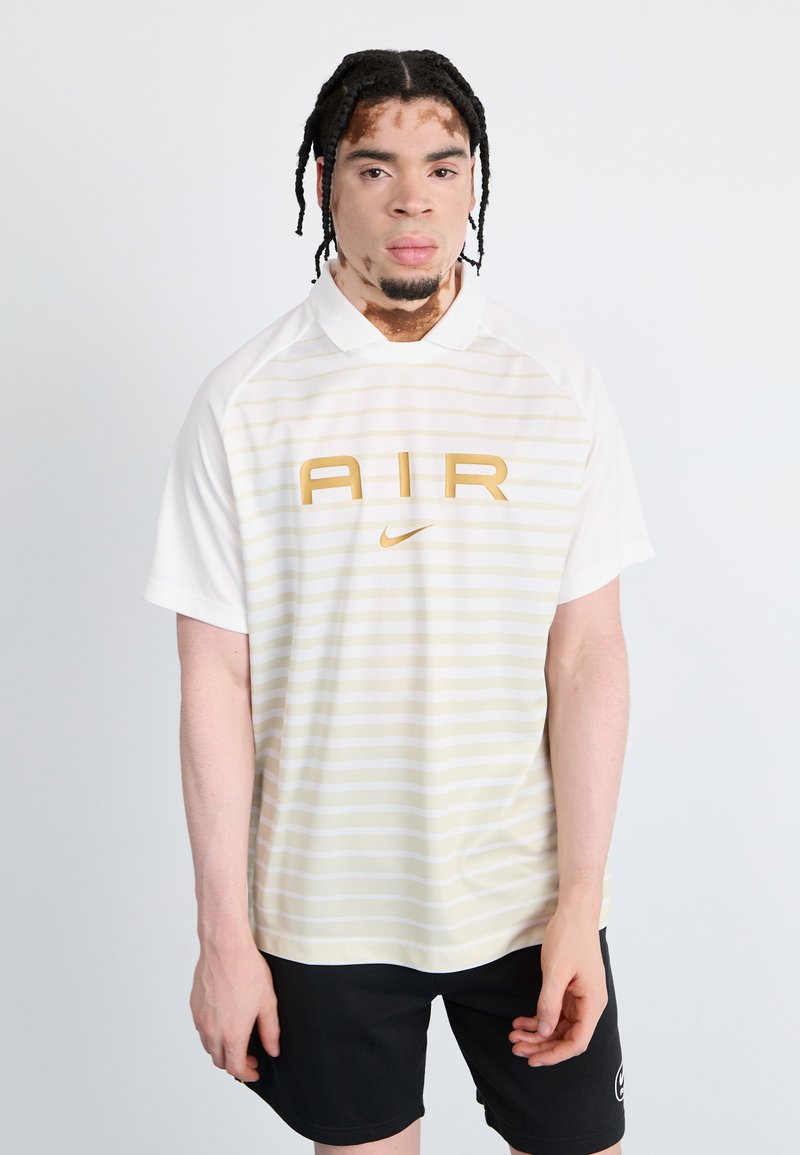 White short-sleeve polo shirt with horizontal light yellow stripes, featuring a large gold 'AIR' logo and Nike swoosh. Black shorts.