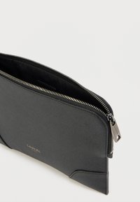 Fekete bőrtáska texturált felülettel, cipzáros záródással és egy "LANCEL" feliratos dombornyomott fém címkével. Belül fekete szövetbéléssel.