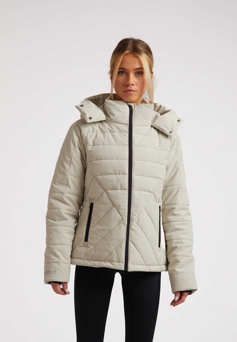 Chaqueta aislante gris claro con cuello alto, patrón de acolchado en diagonal y bolsillos con cremallera negra. Cremallera en el frente, diseño con capucha.