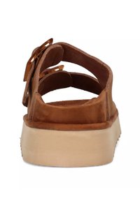 Bruine suède sandalen met verstelbare banden, platte zool en een lichtbruine rubberen basis, met een eenvoudig ontwerp en textuur.