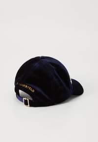Dunkelblaues Samt-Baseballcap mit gebogenem Schirm, das goldene Stickerei mit der Aufschrift "KARL LAGERFELD" auf der Rückseite und einen Metallverschluss hat.