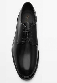 Scarpa elegante in pelle nera con finitura liscia, punta rotonda e design con lacci; include cuciture sottili e una suola leggermente rialzata.