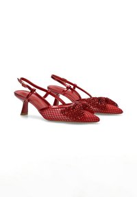 Zapatos de tacón rojo tipo slingback con diseño de malla, punta afilada y un lazo adornado con acentos brillantes. Tacón bajo con una curva sutil.