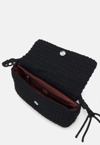 Borsa in tessuto nero intrecciato con un'esterno testurizzato, chiusura a scatto magnetico e fodera interna rossa. Presenta lati con cordoncini regolabili.