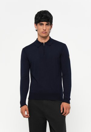Polo de manga larga azul marino con cuello con cremallera, puños acanalados y un diseño ajustado, hecho de un material de punto suave.