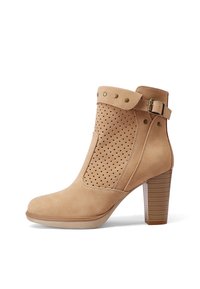 Stivale alla caviglia beige in suede con design perforato, dettaglio con fibbia e tacco impilato. Presenta una punta tonda e una suola a contrasto.