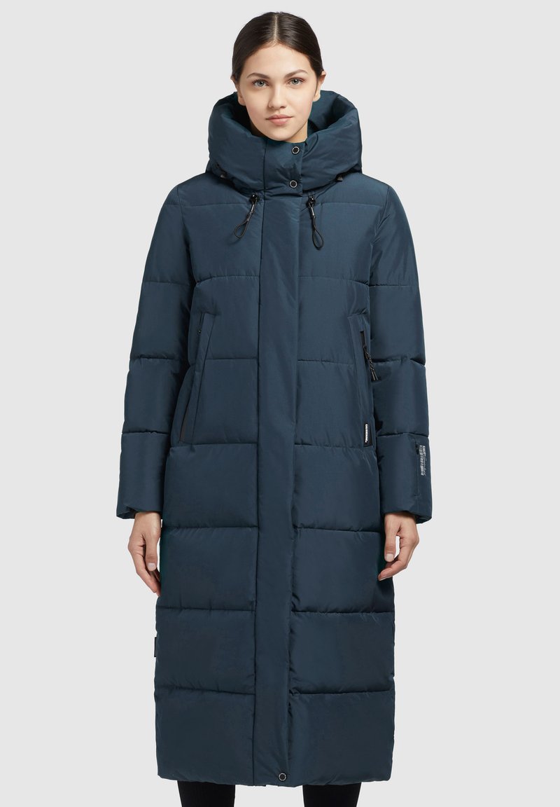Abrigo de invierno largo y acolchado en azul oscuro. Presenta un cuello alto con cordones ajustables, bolsillos laterales con cremallera y una silueta recta.