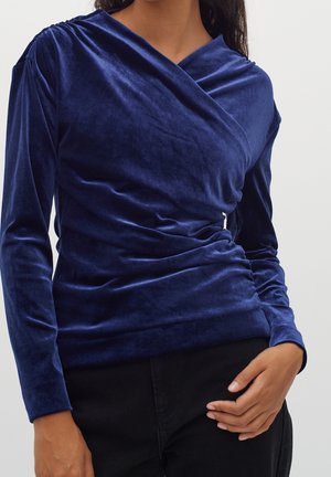 Top in velluto blu navy con maniche lunghe, design a drappo avvolgente e leggera arricciatura sul lato. Texture liscia e silhouette aderente.