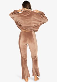 Rjav rebrast kord na loungewear set, ki vsebuje ohlapen srajčni del in široke hlače z gladko teksturo in elastičnim pasom.