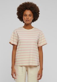 Pasiasta, krótki rękaw t-shirt w miękkim beżowym kolorze z jasnoróżowymi paskami, wykonany z bawełny. Posiada okrągły dekolt i luźny krój.