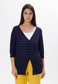Cardigan blu navy con maniche a tre quarti, caratterizzato da motivi a righe orizzontali e piccoli intagli. Chiusura con bottoni davanti e materiale in maglia leggera.