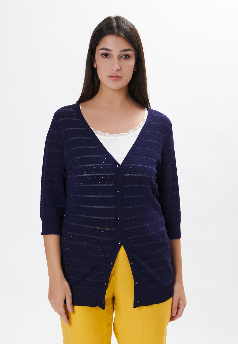 Cardigan blu navy con maniche a tre quarti, caratterizzato da motivi a righe orizzontali e piccoli intagli. Chiusura con bottoni davanti e materiale in maglia leggera.