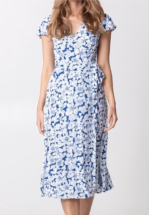 Robe portefeuille fleurie en bleu et blanc, avec des manches courtes à volants, un décolleté en V et une ceinture nouée sur le côté. Tissu doux avec une silhouette fluide.