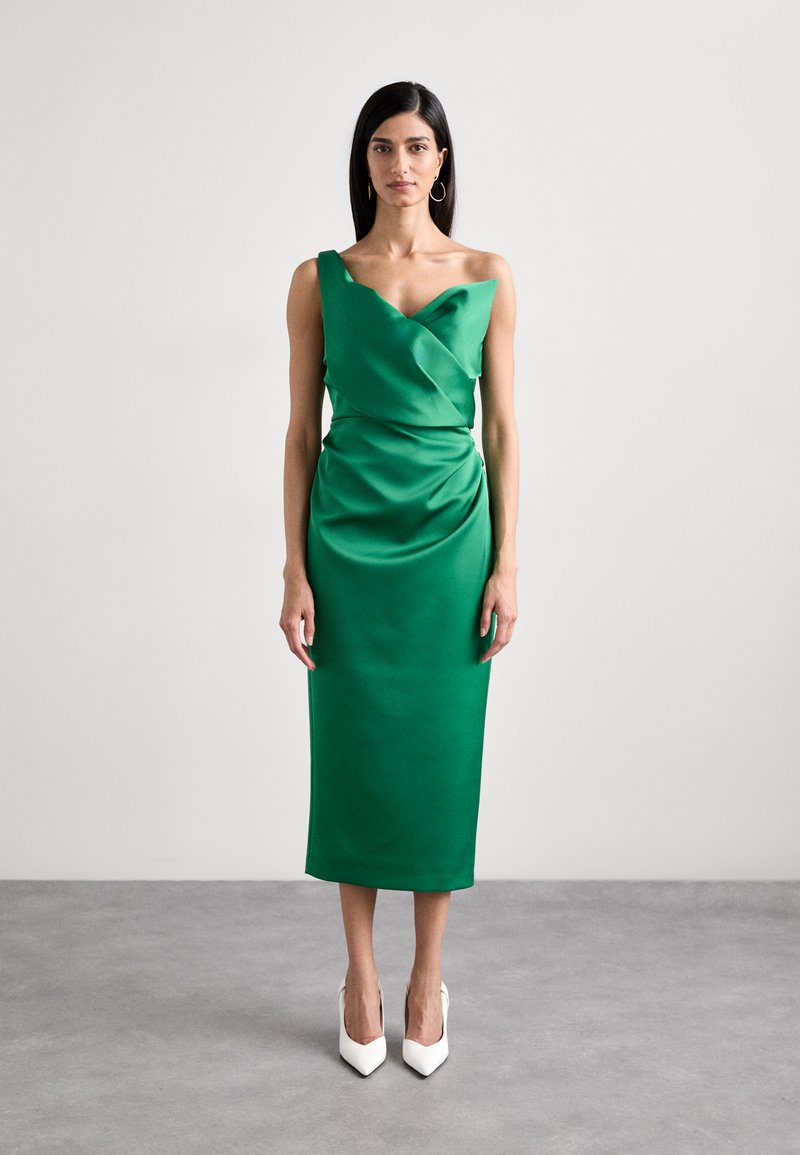 Green satin dress with a draped front, one shoulder design, and knee-length cut. Worn with pointed white heels. Smooth texture.