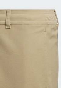 Pantalones caqui beige con una textura suave, parte delantera plana, bolsillos laterales y una trabilla en la cintura. Construcción simple, sin patrones visibles.