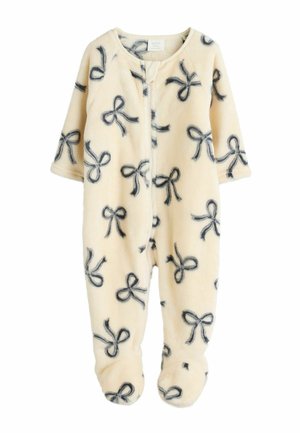 Krämfärgad fleeceoverall med svart rosetttryck, långa ärmar, dragkedjestängning och fotsydd design. Mjukt material och mysig utseende.