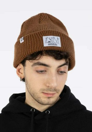 Ruskea ribattuja beanie, jossa on logopainatus ja graafinen suunnittelu. Pehmeä rakenne, tiukka istuvuus ja klassinen, taitettava cuff-suunnittelu.