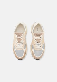 Beige und weiße Sneaker mit Mesh- und Wildlederelementen. Merkmale sind eine runde Zehenpartie, Schnürdesign und eine kontrastierende Gummisohle. GANT-Logo auf der Zunge.