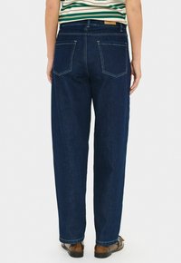 Tumed sinised denim teksad lõdva lõikega, millel on kaks tagataskut, nähtav õmblemine ja sirge sääre disain.