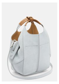 Jasnoniebieska torba typu bucket zamszowa z brązową skórzaną rączką, wyposażona w kieszeń na suwak z boku oraz subtelne przeszycie. Regulowany pasek na ramię.