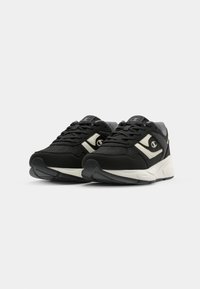 Black sneakers featuring a textured fabric upper, white and gray accents, and a cushioned sole with a prominent logo on the side.