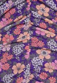 Tecido com padrão floral em roxo, apresentando várias flores em rosa, laranja e branco. A textura parece suave, com um detalhe sutil de franzido.