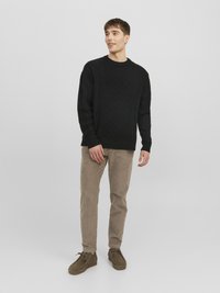 Maglione nero lavorato a maglia con un motivo a diamante testurizzato, abbinato a pantaloni di velluto a coste color marrone chiaro e scarpe in pelle marroni.