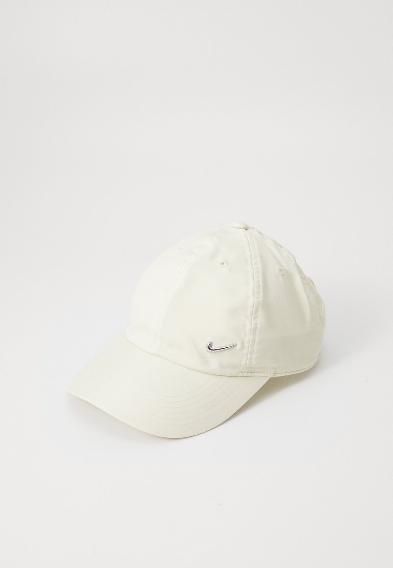 Balts Nike cepure ar mīkstu audumu, izliekto vizieri, sešu panelu dizainu un mazu sudraba logo kreisajā pusē.