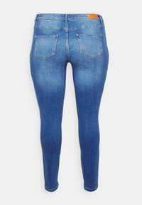 Blue skinny jeans made of denim with a smooth texture, featuring a waistband and two rear pockets, and a brown leather patch at the back.