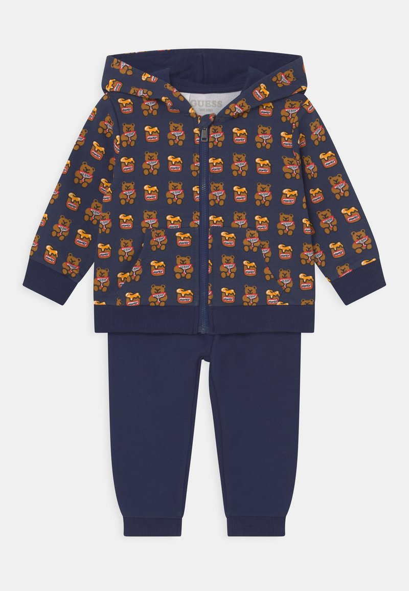 Tuta da ginnastica blu navy con felpa con zip caratterizzata da un motivo di orsi e miele, accompagnata da pantaloni abbinati. Realizzato in tessuto morbido con polsini a coste.