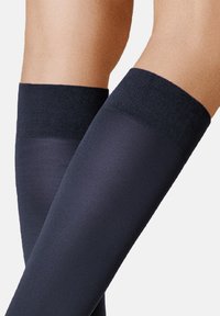 Kniehohe Kompressionssocken in tiefem Marineblau. Glatte Textur mit einer einfarbigen Optik und einem gerippten schwarzen Bündchen oben für einen sicheren Sitz.