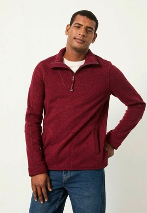 Burgunderfarbener Half-Zip-Pullover aus strukturiertem Fleece. Verfügt über Seitentaschen und kontrastierende Nähte. Mit hohem Kragen und lässiger Passform gestaltet.