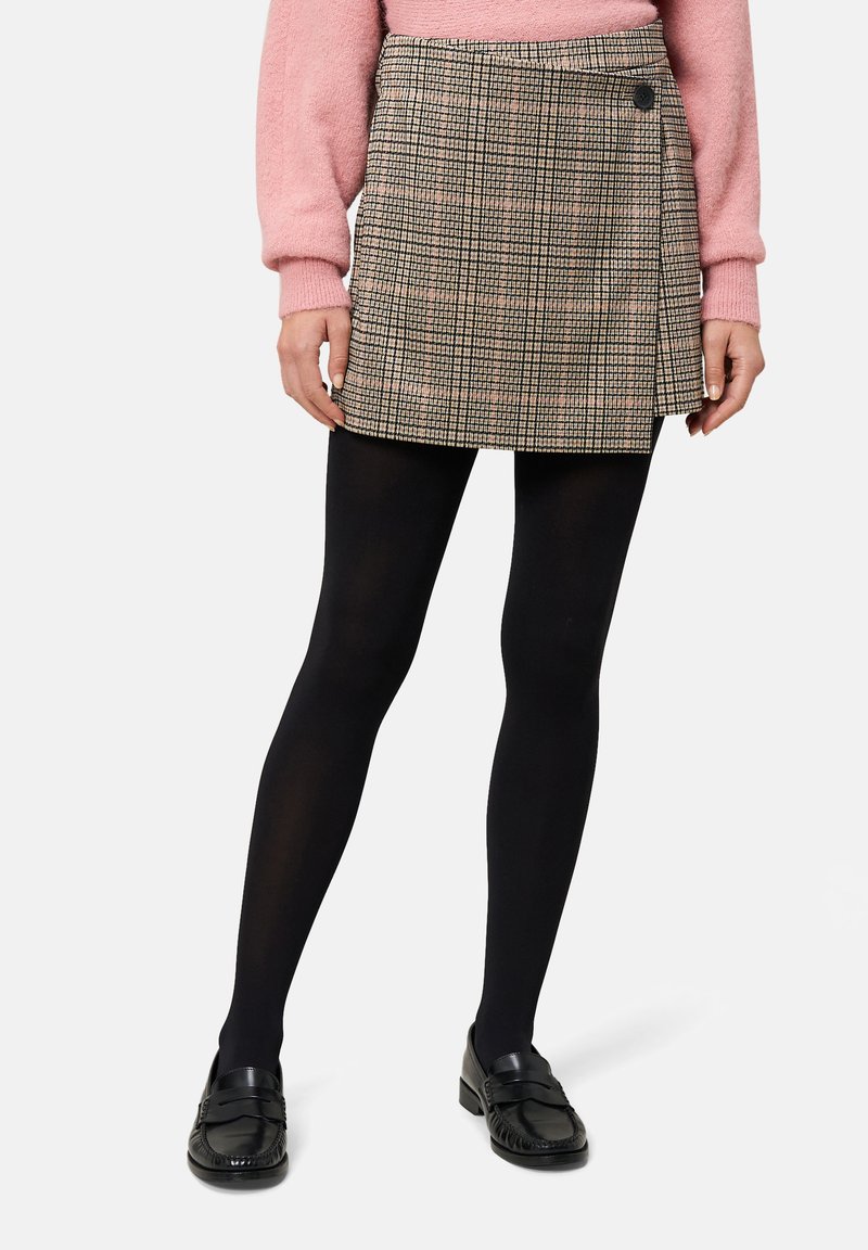 Rutete mininederdel i beige, brun og sort med asymmetrisk overslagsdesign og en sideknap. Kombineret med sorte strømpebukser og loafers.