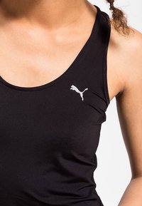 Černý bezrukávový sportovní top vyrobený z hladkého materiálu, s malým stříbrným logem Puma na levé části hrudi. Zaoblený výstřih a přiléhavý střih.