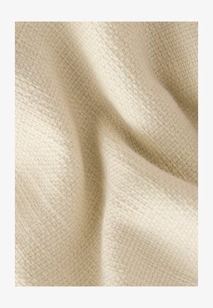 Struktureret cremet stof med et vævet mønster, der viser bløde folder og subtile variationer i lyset, hvilket indikerer et let og åndbart materiale.