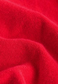 Gros plan d’un tissu éponge doux et rouge vif montrant une texture détaillée et des plis légers.