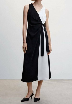 Vestido en blanco y negro con bloques de color y diseño envolvente, que presenta un detalle de cintura anudada, corte sin mangas y tela fluida.
